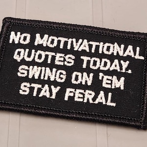 May include: A rectangular black embroidered patch with a stitched border. The white text reads: NO MOTIVATIONAL QUOTES TODAY. SWING ON 'EM STAY FERAL. The patch features a dense fabric texture and clear, bold lettering in a sans-serif font style.