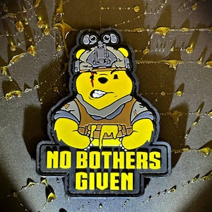 May include: A yellow bear character patch wearing a tactical helmet with night vision goggles and a brown vest. The bear has a red scar over one eye and a determined expression. Below the bear, the text reads NO BOTHERS GIVEN in yellow letters.