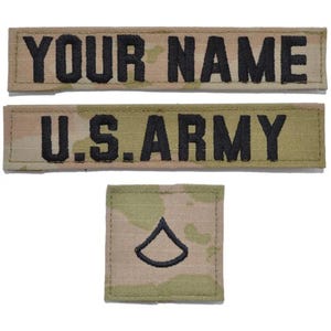 May include: Two rectangular fabric patches with camouflage patterns and black embroidered text reading YOUR NAME and U.S. ARMY, accompanied by a square patch featuring a single black embroidered chevron rank insignia on a matching camouflage background.