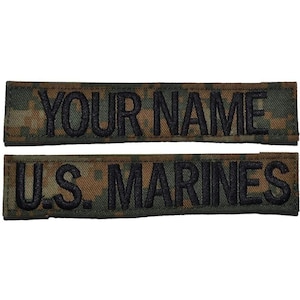 May include: Two rectangular embroidered patches featuring a digital camouflage pattern in shades of brown, green, and black. The top patch displays the text YOUR NAME in black block letters, while the bottom patch displays U.S. MARINES in black.