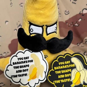 May include: A yellow plush banana toy with a black mustache and angry expression, accompanied by two cloud-shaped patches featuring a yellow banana illustration and the text: YOU EAT BANANA'S FOR THE SHAPE AND NOT THE TASTE!