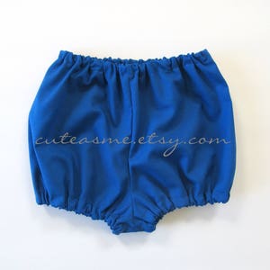 May include: Royal blue baby bloomers with a gathered elastic waistband. The bloomers are made of a soft, comfortable fabric.