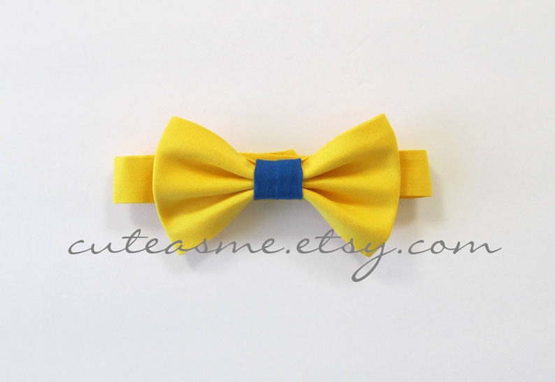 May include: A yellow bow tie with a blue center. The bow tie is made of fabric and has a simple design.