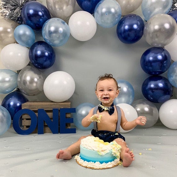 sesión smashcake, previa al pastel, niño con pluri discapacidad de 3 años  mira y observa con peto y gorro tipo boina Stock Photo