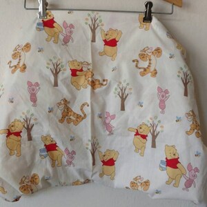 May include: White Winnie the Pooh and Tigger themed fabric with a repeating pattern of Winnie the Pooh, Tigger, and Piglet characters. The fabric features a white background with yellow, red, and brown accents.