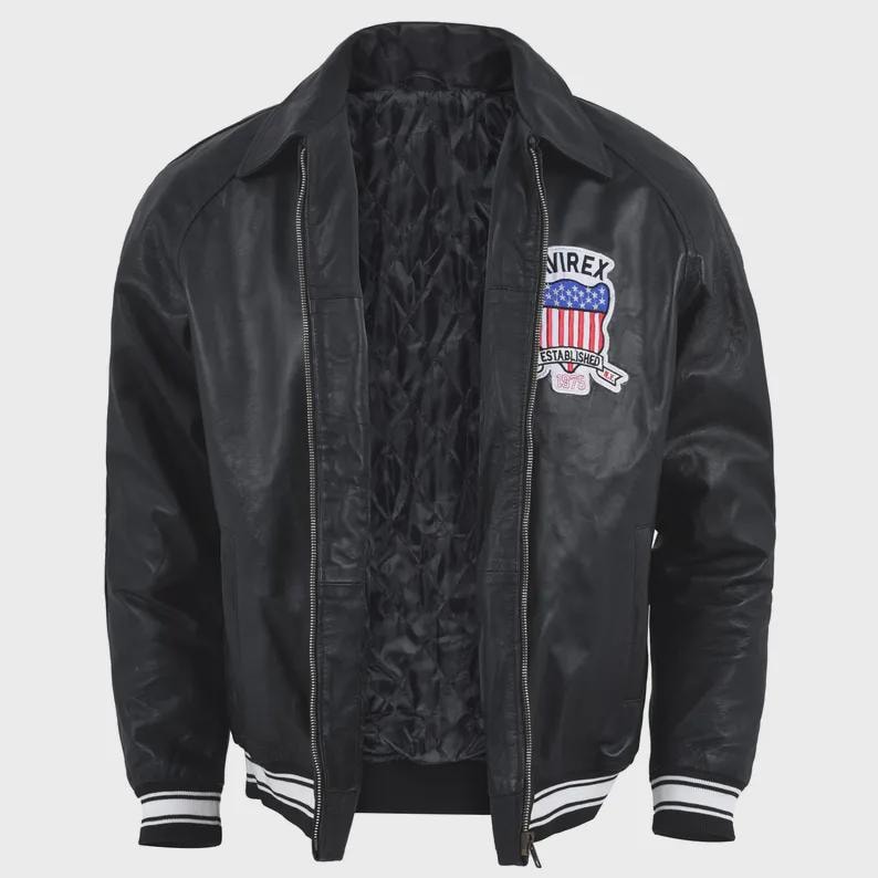 May include: A black jacket with a front zipper closure, a quilted interior lining, and a collar. The chest features a patch with the text "AVIREX ESTABLISHED 1975" and a shield graphic with red, white, and blue stripes. The cuffs and hem have white stripes.