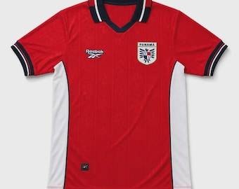 May include: A red short-sleeved jersey with a V-neck collar in navy blue and white. The shirt features white side panels, the Reebok logo in white on the right chest, and the Panama national crest with the text PANAMÁ on the left chest.