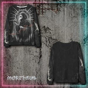 May include: A black long-sleeve sweatshirt featuring a graphic of a plague doctor in a hooded robe holding a censer. The design includes a circular halo and thorny vine patterns on the sleeves. The text MORTHAUS is printed in a gothic font.