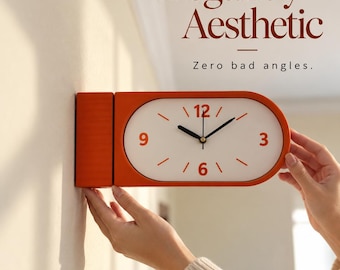 May include: An orange wall clock with a white face, black hands, and orange numerals for 3, 6, 9, and 12. The clock has a rounded rectangular shape and is mounted to a wall. The text "Elegantly Aesthetic" and "Zero bad angles." appears above.