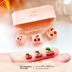 Peut inclure: Un ensemble d'emporte-pièces en argile couleur pêche claire en forme de cerise avec un cadre rectangulaire et trois petits inserts carrés. Le texte Pearnmade Cutters Digital Download et Bambu Lab Include STL & 3MF Files for Bambu Studio est visible.