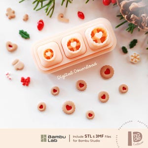 May include: A light peach-colored plastic cookie cutter set with three square-shaped molds featuring heart-shaped centers. The text Digital Download is visible. Small round cookies with red heart centers are scattered around the cutter set.