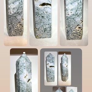 May include: A moss agate crystal tower featuring a pointed top and a hexagonal base. The stone displays a translucent white and grey base with intricate, dark green, fern-like dendritic inclusions and small natural cavities throughout the surface.