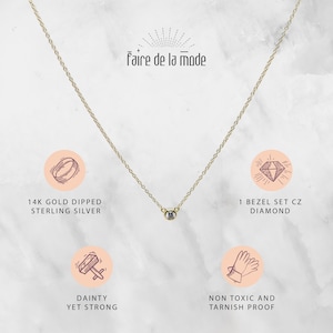 May include: A delicate gold-colored necklace with a single bezel-set CZ diamond pendant. The necklace is labeled "faire de la mode" and is described as 14K gold dipped sterling silver, dainty yet strong, and non-toxic and tarnish proof.