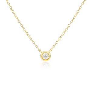 May include: A delicate gold necklace featuring a single, round, clear gemstone pendant. The pendant is set in a bezel setting and hangs from a fine gold chain. The necklace is displayed against a white background.