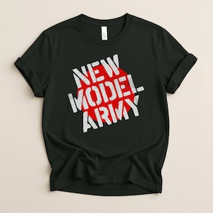 Pode incluir: Uma t-shirt preta de manga curta com um gráfico de um círculo vermelho grande no peito. Sobreposto ao círculo vermelho está o texto branco NEW MODEL ARMY com efeito desgastado em três linhas. A t-shirt tem gola redonda e corte padrão.