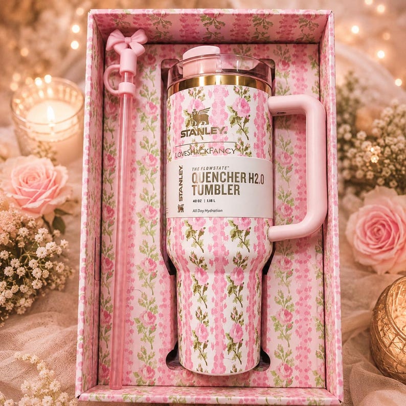 May include: A 40 oz Stanley Quencher H2.0 tumbler with a pink and green floral pattern, featuring a matching straw with a bow topper, housed in a floral-patterned box. The tumbler has a handle, a clear lid, and the text Stanley LoveShackFancy.