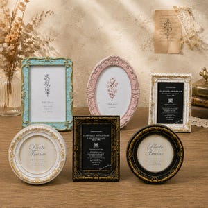 Puede incluir: Una colección de seis marcos de fotos decorativos de diversas formas y colores, incluyendo diseños rectangulares y ovalados en azul claro, rosa, blanco y negro con detalles dorados y láminas impresas con motivos florales.