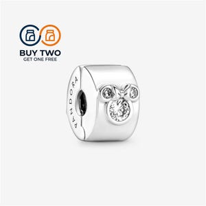 Pode incluir: Um berloque Pandora de prata com acabamento polido e um motivo central de Mickey Mouse. O design inclui três pedras transparentes de corte redondo cravadas nas orelhas e no rosto do ícone. A palavra PANDORA está gravada na lateral.
