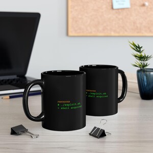 May include: Two black ceramic mugs featuring the orange text PENTESTER and green terminal command text that reads ./exploit.sh followed by shell acquired. The mugs have a standard handle and a smooth, glossy finish, displaying the same code.
