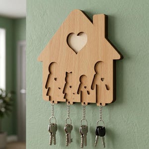 May include: A light brown wooden wall-mounted key holder shaped like a house. The design features a cutout heart at the top and four stylized human silhouettes below. Four silver metal chains hang from the bottom, each holding a metal key.