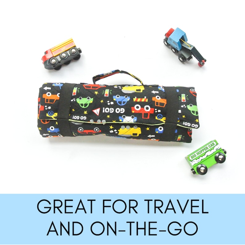 May include: A black and yellow play mat with a car print. The mat is rolled up and has a handle. There are toy cars around the mat.
