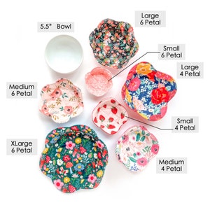 May include: A set of 9 fabric bowl cozies in various sizes and floral patterns. The cozies are in pink, red, green, and blue floral patterns. The cozies are labeled with their size and number of petals. The largest cozie is 6 petals and is labeled "XLarge 6 Petal". The smallest cozie is 4 petals and is labeled "Small 4 Petal".