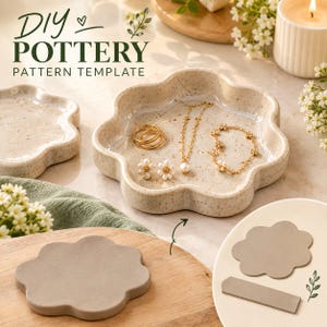 Puede incluir: Un conjunto de plantillas para cerámica DIY que incluye un plato de cerámica beige moteado en forma de flor con anillos dorados, un collar de perlas y una pulsera. El set contiene un recorte de arcilla gris y una herramienta rectangular.