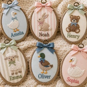 Puede incluir: Seis bastidores de bordado ovalados con animales cosidos: una oca llamada Amelia, un conejo llamado Noah, un oso llamado Henry, una oveja llamada Emma, un pato llamado Oliver y un cisne llamado Sophia. Cada bastidor tiene un lazo de sat&eacute;n.