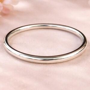 Peut inclure: Un bracelet jonc circulaire en argent poli et lisse avec un profil arrondi. La surface métallique est hautement réfléchissante, présentant un design en boucle continue et épuré sans fermoirs, charnières ou éléments décoratifs ajoutés.
