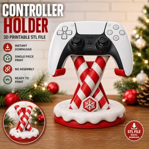May include: A white and black game controller resting on a 3D printable controller holder shaped like two crossed red and white candy canes on a snow-covered circular base with a snowflake emblem. Text includes CONTROLLER HOLDER.