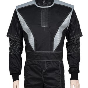 May include: A black long-sleeve jumpsuit featuring a high collar and silver-grey quilted shoulder panels. The sleeves have a white geometric grid pattern, and the garment is accented with white contrast stitching throughout the torso and legs.
