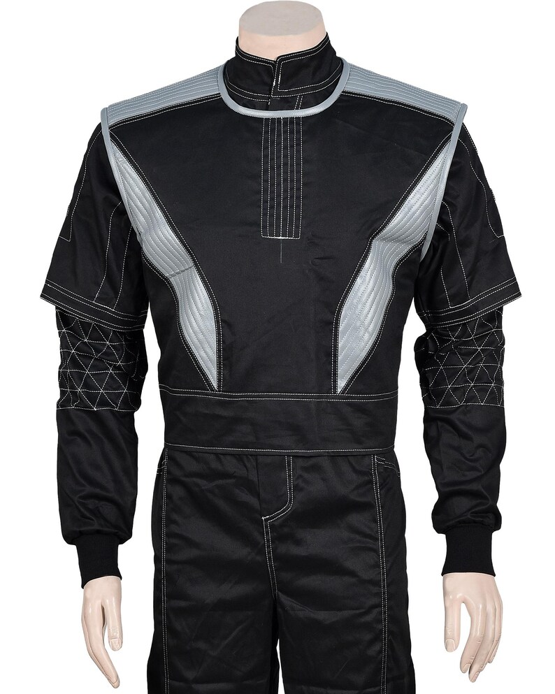 May include: A black long-sleeve jumpsuit featuring a high collar and silver-grey quilted shoulder panels. The sleeves have a white geometric grid pattern, and the garment is accented with white contrast stitching throughout the torso and legs.