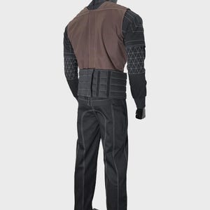 May include: A full-body costume on a mannequin featuring a black long-sleeved top with white geometric stitching, a brown vest, a wide black ribbed waist belt with vertical panels, and black trousers with prominent white seam detailing throughout.