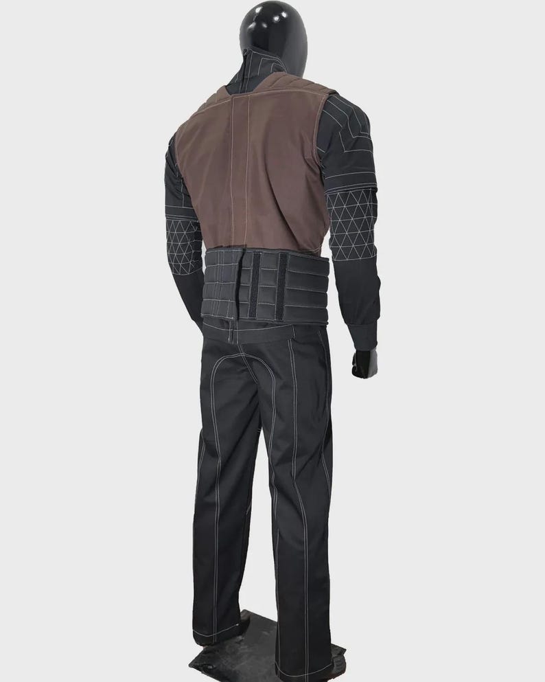 May include: A full-body costume on a mannequin featuring a black long-sleeved top with white geometric stitching, a brown vest, a wide black ribbed waist belt with vertical panels, and black trousers with prominent white seam detailing throughout.