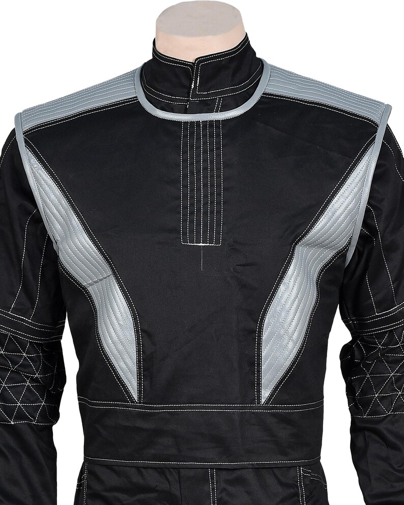 May include: A black long-sleeve jacket featuring silver-grey quilted panels on the shoulders and chest, a high collar, and white contrast stitching. The sleeves include a geometric quilted pattern on the forearms and a structured design.