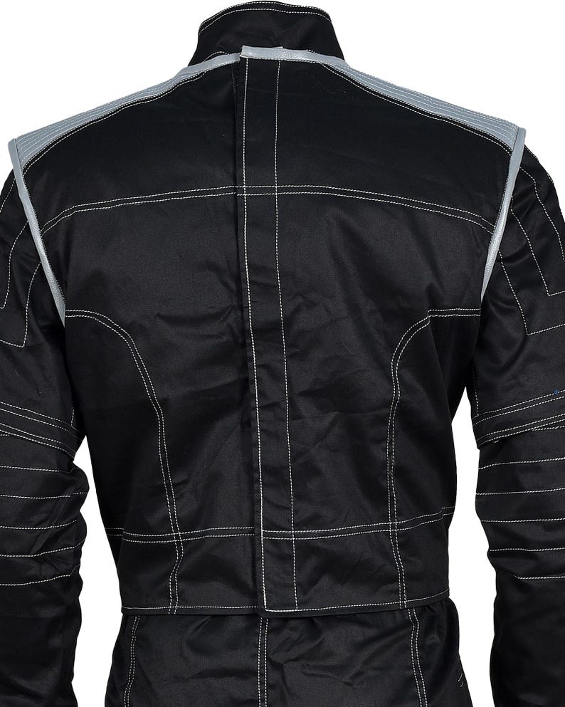 May include: A black racing jacket featuring a high collar, long sleeves, and prominent white contrast stitching throughout. The garment includes light gray panels on the shoulders and upper back, with a central vertical seam running down the back.