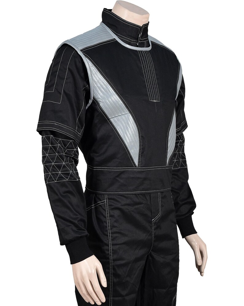 May include: A black and grey tactical-style jacket featuring a high collar, a front zipper closure, and quilted grey panels on the chest and shoulders. The sleeves include a geometric stitched pattern, and the garment has white contrast stitching.