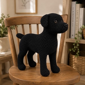 May include: A black crocheted dog figurine featuring a textured yarn surface, floppy ears, a small black nose, and brown eyes. The stuffed animal is standing in a profile position, showcasing its four legs and a short tail, crafted with detailed stitching.