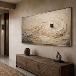 May include: A large rectangular wall art piece featuring a textured, impasto-style painting in shades of beige, cream, and dark grey. The artwork depicts a central black cube surrounded by a swirling, circular pattern of small, indistinct figures.
