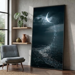 May include: A large rectangular framed wall art piece featuring a dark night scene with a glowing crescent moon above a shimmering body of water. A trail of sparkling light descends from the moon, reflecting brightly on the dark rippling surface.