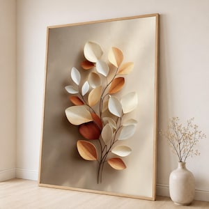 May include: A framed wall art piece featuring a central botanical illustration of a branch with layered, three-dimensional-style leaves in shades of cream, beige, and burnt orange against a smooth, gradient tan background.