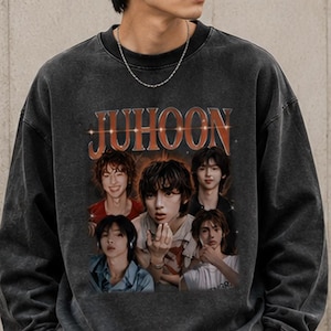 May include: A charcoal gray crewneck sweatshirt featuring a vintage-style graphic print on the front. The design includes the text JUHOON in a bold, serif font above a collage of five portraits of a person in various poses and outfits.