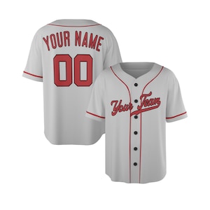 Può includere: Una maglia da baseball grigio chiaro con finiture rosse, dotata di chiusura a bottoni, maniche corte e scritta rossa Your Team sul davanti, con Your Name e il numero 00 in rosso sul retro della maglia.
