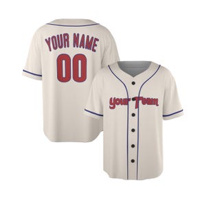 Può includere: Una maglia da baseball color crema a maniche corte, con chiusura a bottoni e profili blu. La parte anteriore presenta la scritta "your Team" in rosso, mentre il retro mostra "YOUR NAME" e il numero "00" in rosso con bordi blu.