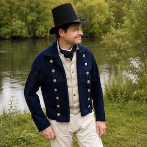 Può includere: Un cilindro nero, una giacca doppiopetto blu navy con bottoni dorati, un gilet beige chiaro con bottoni abbinati e un fazzoletto da collo nero. L'insieme comprende pantaloni beige chiaro, creando un abbigliamento dallo stile storico.