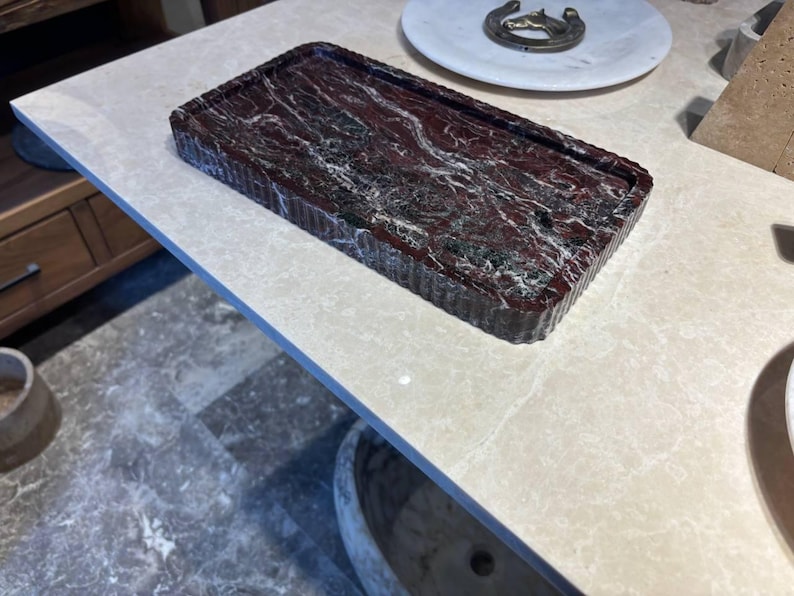 May include: A rectangular tray featuring a deep red and black marbled pattern with white veining. The tray has a distinctively ribbed or fluted texture along its outer vertical edges, creating a structured and consistent appearance throughout the piece.