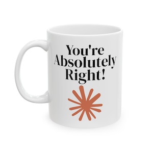 May include: A white ceramic mug featuring the black text "You're Absolutely Right!" printed in a serif font. Below the text is a stylized, terracotta-colored sunburst or starburst graphic with multiple radiating lines centered on the mug.