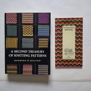 May include: Two books on knitting. The left book is titled A Second Treasury of Knitting Patterns by Barbara G. Walker, featuring a black cover with colourful knitted swatches. The right book is The Pattern Library Knitting with a chevron pattern.