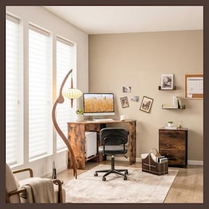 May include: A home office setup featuring a corner desk with a rustic wood finish, a black swivel chair, and a tall, curved floor lamp with a white lantern-style shade. A matching three-drawer filing cabinet and a brown storage bin sit nearby.