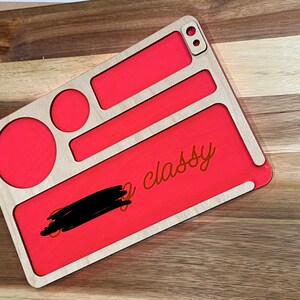 May include: A wooden rolling tray with a red, felt-like lining. The tray has multiple compartments and a cutout for a lighter. The text "So classy" is written on the tray.